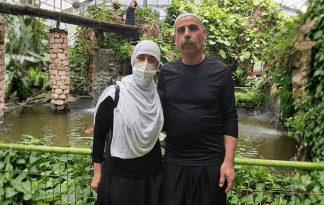 Two people standing together in a lush indoor garden with waterfalls